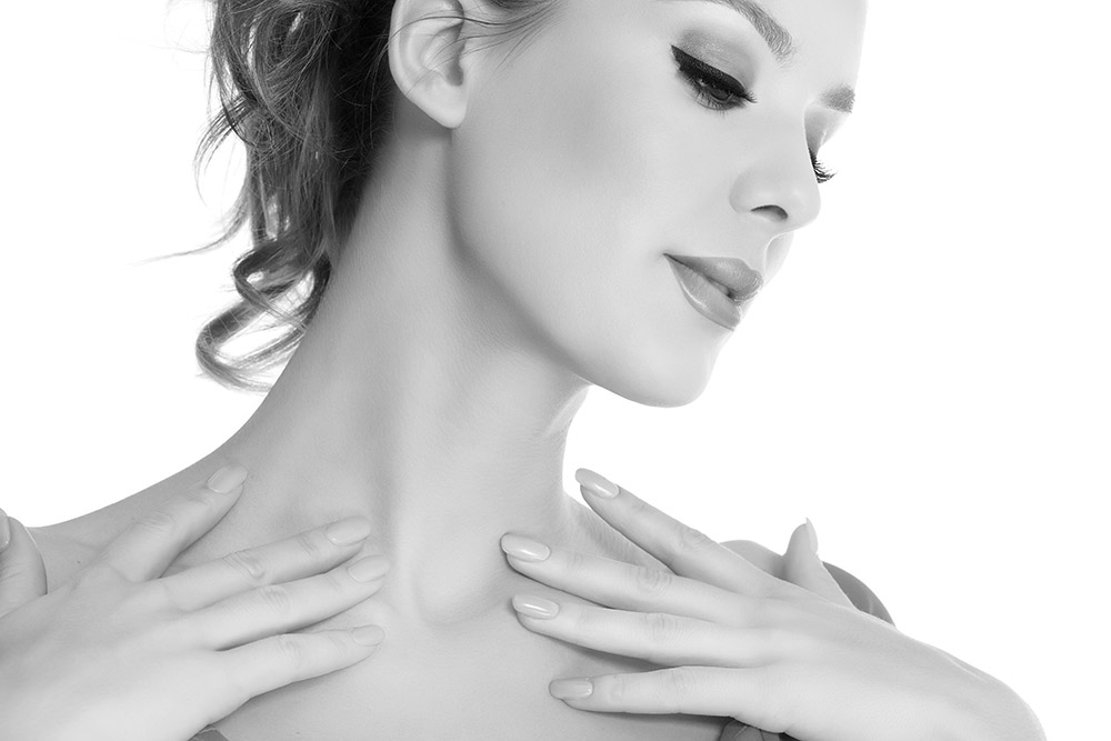 Woman touching her collarbones, looking downt to the side