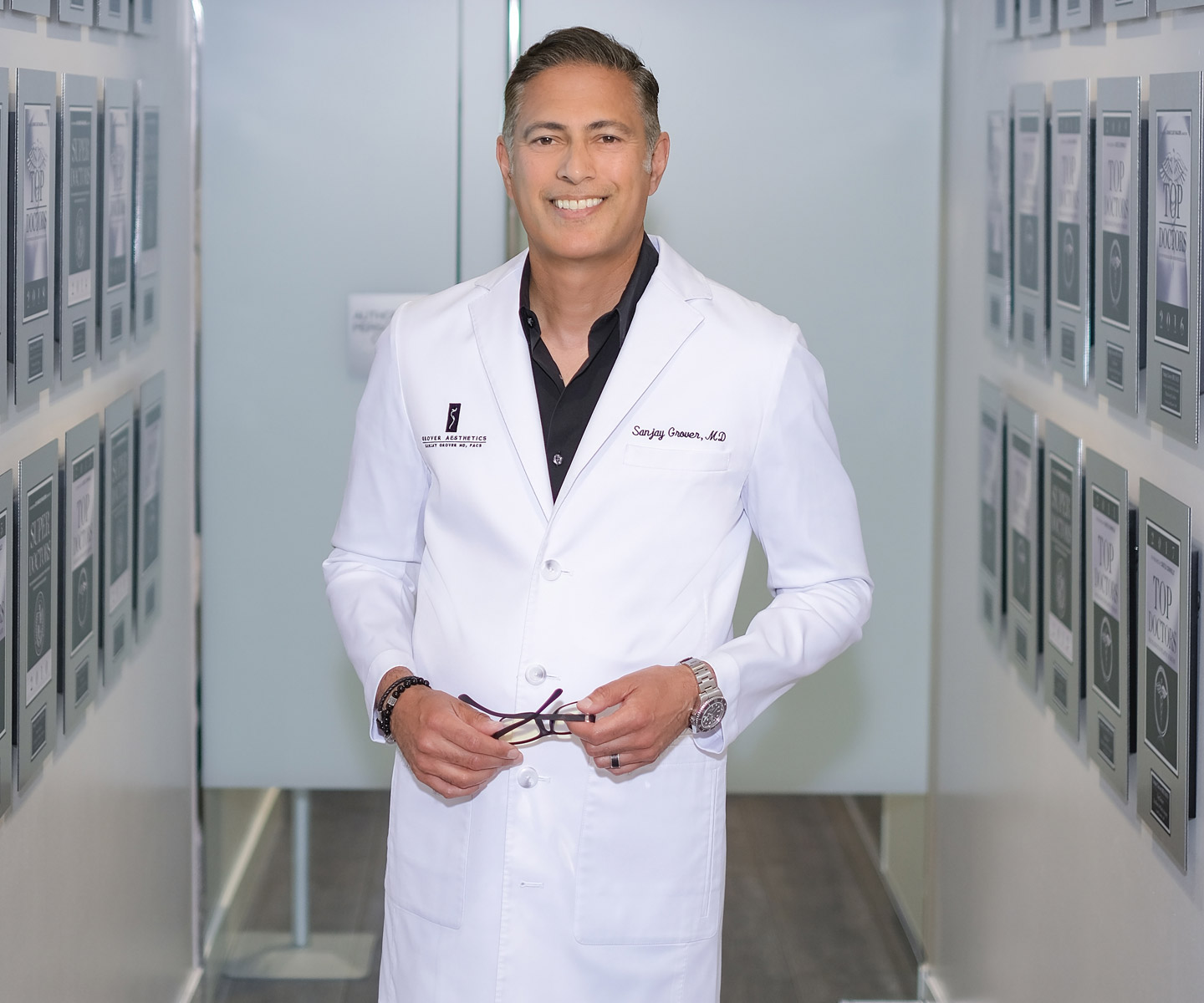 Dr. Grover smiling, standing in hallway of his awards